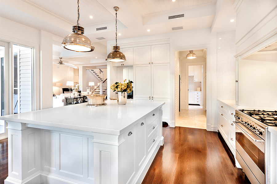 kitchen-with-large-white-island-and-hanging-lights-and-wood-floors-houston-tx